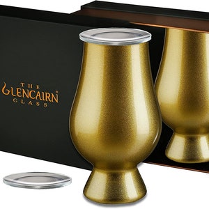 Pode incluir: Dois copos de whisky Glencairn dourados com tampas em uma caixa preta. A caixa tem o texto "The Glencairn Glass" na frente.