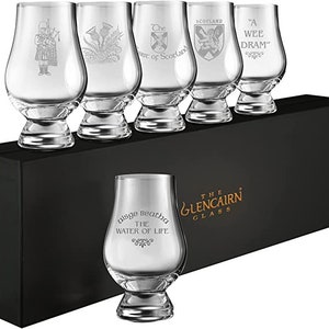 Puede incluir: Un juego de seis vasos de whisky Glencairn transparentes, cada uno grabado con s&iacute;mbolos y frases escocesas, incluyendo un gaitero, un cardo y las palabras "Scotland" y "A Wee Dram". Los vasos se presentan en una caja negra con "The Glencairn Glass" impreso.