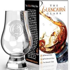May include: A clear glass Glencairn whisky glass with a wide base and a rounded bowl. The glass is etched with the words "Hamilton Through" and a crest. The glass is on a white surface. The Glencairn Glass is the official whisky glass.
