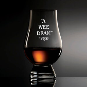 Puede incluir: Una copa de degustaci&oacute;n de whisky transparente con las palabras "A WEE DRAM" en letras blancas. La copa est&aacute; parcialmente llena de l&iacute;quido color &aacute;mbar. La copa tiene un cuerpo bulboso y un borde acampanado, con un tallo corto y una base ancha.