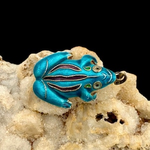 May include: A blue enamel frog charm with silver accents and a loop for attaching to a necklace or bracelet.