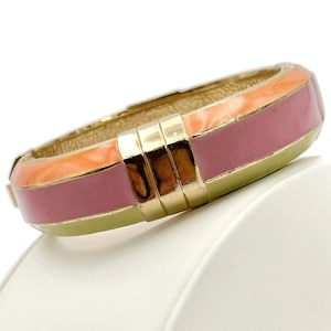 May include: A gold bangle bracelet with a pink, orange, and yellow enamel design.
