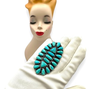 Könnte beinhalten: Eine Brosche aus Türkis und Silber im Stil der amerikanischen Ureinwohner mit einer Gruppe von Türkis-Steinen in Blattform.