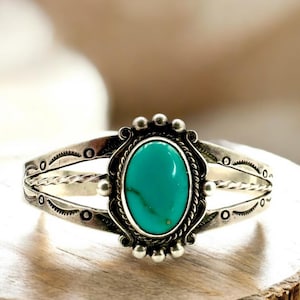 May include: A silver bracelet with a turquoise stone set in a decorative silver bezel. The bracelet has a twisted wire design and is accented with small silver beads.