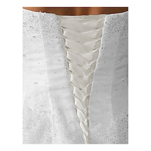 Puede incluir: Vestido de novia blanco con la espalda de encaje. La espalda del vestido está adornada con pequeñas cuentas blancas.