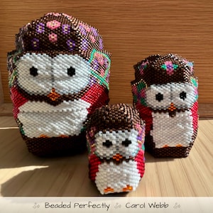 Peut inclure: Trois figurines de hiboux perlés de tailles variées. Les hiboux présentent des perles marron, blanches, rouges et violettes, avec des yeux noirs et des becs oranges. Le texte "Beaded Perfectly Carol Webb" est en bas.