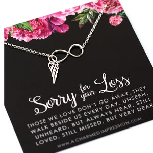 May include: A silver infinity necklace with a small angel wing charm. The necklace comes with a black card that reads "Sorry for your Loss. Those we love don't go away, they walk beside us every day. Unseen, unheard, but always near, still loved, still missed, but very dear. www.A CHARMED IMPRESSION.COM"