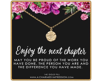 May include: A gold necklace with a round pendant featuring a star design, displayed on a black card with pink floral accents. The card text reads: Enjoy the next chapter. May you be proud of the work you have done, the person you are and the difference you have made. 14k gold fill.