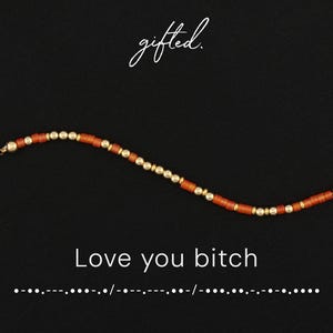 May include: A beaded bracelet featuring alternating burnt orange cylindrical beads and small metallic gold spherical beads. The text gifted. appears above the bracelet, while the text Love you bitch and Morse code are printed below it.