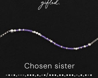 May include: A beaded bracelet featuring alternating purple cylindrical beads and small silver spherical beads. The text "gifted." appears at the top, with "Chosen sister" and a Morse code sequence printed in white below the jewelry piece.