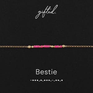 May include: A gold-colored chain bracelet with a series of small, bright pink beads and gold-colored beads. The word "Bestie" is displayed in white text below the bracelet, with the word "gifted" in cursive at the top.