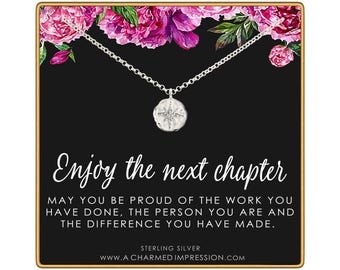 May include: A sterling silver necklace with a small, round, textured pendant featuring a starburst design. The necklace is displayed on a black card with pink floral accents and the text: Enjoy the next chapter. MAY YOU BE PROUD OF THE WORK YOU HAVE DONE, THE PERSON YOU ARE AND THE DIFFERENCE YOU HAVE MADE. STERLING SILVER WWW.A CHARMED IMPRESSION.COM