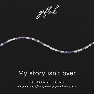 Könnte beinhalten: Eine Perlenkette mit abwechselnden metallisch silbernen Kugeln und zylindrischen violetten Perlen. Der Text gifted. steht oben, während der Satz My story isn't over und der entsprechende Morsecode darunter abgedruckt sind.