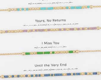 May include: Four gold-tone chain bracelets featuring colored beads arranged in Morse code patterns. The phrases I Choose You, Yours, No Returns, I Miss You, and Until the Very End are printed above each corresponding turquoise, lavender, green, and blue beaded bracelet.