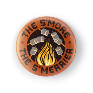 May include: A round, orange button with the text "THE S'MORE THE S'MERRIER" in brown lettering. The button features a campfire graphic with marshmallows roasting over the flames. The design is a fun, camping-themed illustration.