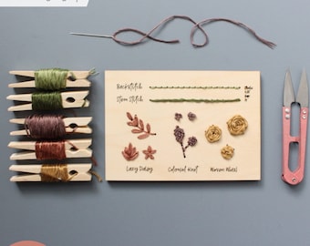 May include: A wooden embroidery kit with a variety of stitches and embroidery floss. The kit includes a wooden board with instructions for backstitch, stem stitch, lazy daisy, colonial knot, and woven wheel. The kit also includes a needle, embroidery floss, and a pair of embroidery scissors.