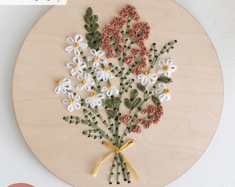 May include: A wooden embroidery hoop with a floral design embroidered in white, green, and pink thread. The text "LASER tested" is visible in the top left corner. The text "SVG LASER FILE | WOOD EMBROIDERY" is visible at the bottom of the image.
