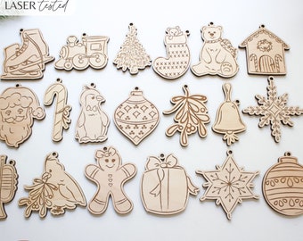 May include: A set of 18 laser-cut wooden Christmas ornaments featuring various designs, including a penguin, a gingerbread person, a Christmas tree, a bell, a snowflake, a stocking, a candy cane, a train, a house, a Santa Claus, a bird, a gift box, and an ornament. The ornaments are all made of natural wood and have a rustic, hand-crafted look.