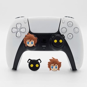 May include: A white PlayStation 5 controller with black accents, customized with character-themed thumb grips. Two brown-haired character thumb grips and a black heartless thumb grip are visible, along with two additional character thumb grips.