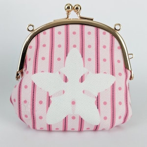 May include: A pink fabric coin purse with a white flower design and a gold metal clasp.