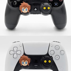May include: Two game controllers, one black and one white, each with character-themed thumb grips. The black controller has Sora and Heartless designs. The white controller has the same designs. Text on the image reads "Fits Playstation/PS4/PS5".