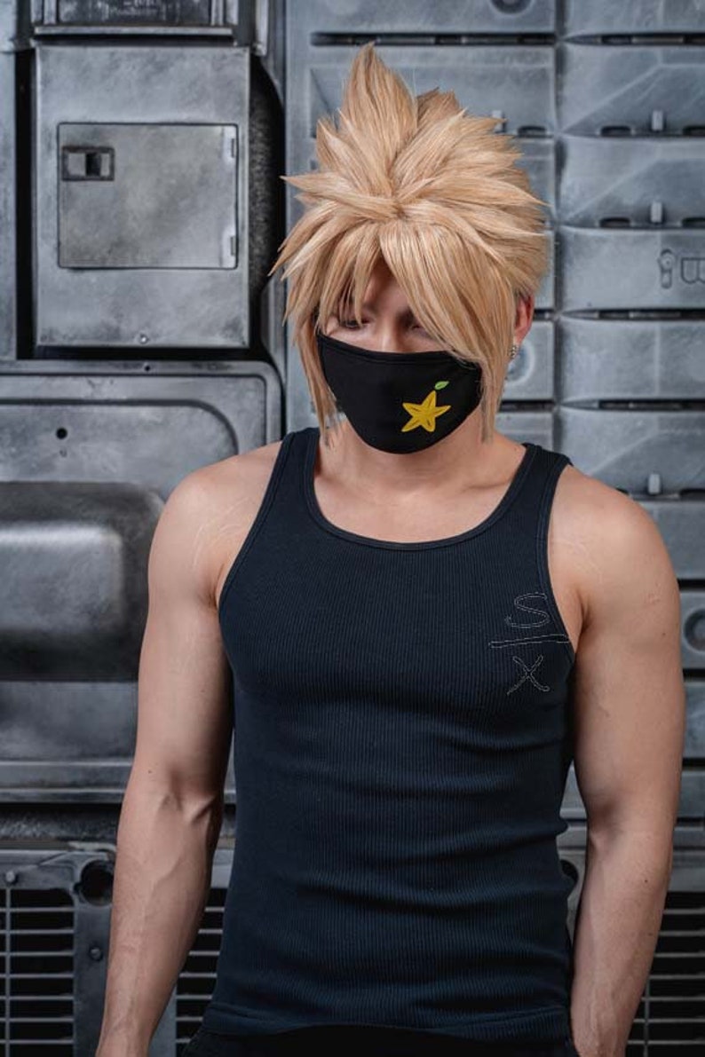 May include: A person wearing a black tank top with a yellow star on a black face mask. The tank top has a white inscription on the front.