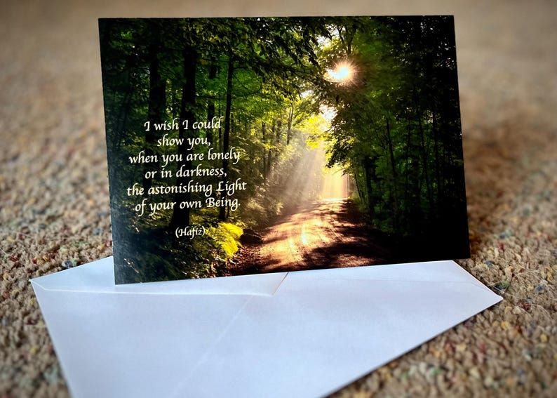 Puede incluir: Una tarjeta de felicitaci&oacute;n con una cita de Hafiz sobre encontrar la luz dentro de ti mismo, con una fotograf&iacute;a de un camino soleado a trav&eacute;s de un bosque.
