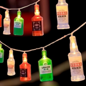 Può includere: Stringa di luci decorative a forma di bottiglie di liquore in miniatura. Le bottiglie sono di vari colori, tra cui rosso, verde e bianco. Alcune bottiglie hanno etichette con la scritta "Vodka Here" e "London Gin."