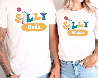 May include: Two white t-shirts with a cartoon seagull holding a red balloon and the word "SILLY" in colorful letters. One shirt says "Dada" and the other says "Mama".