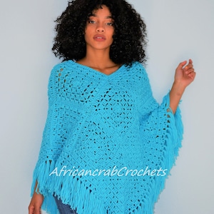 Puede incluir: Un poncho de crochet azul turquesa con flecos. El poncho tiene cuello en V y est&aacute; tejido a crochet en un patr&oacute;n geom&eacute;trico.