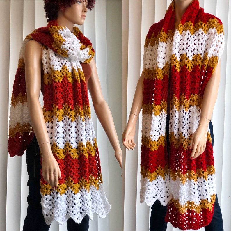 May include: A crocheted scarf with red, white, and gold stripes. The scarf is made with a lacy stitch and has a scalloped edge.