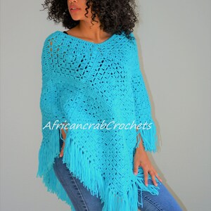 Puede incluir: Un poncho de crochet turquesa con flecos. El poncho lo lleva puesto una persona con el pelo rizado. El texto "AfricancrabCrochets" es visible en el poncho.