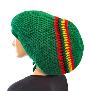 Peut inclure: Un bonnet vert en crochet avec un motif rayé rouge, jaune et noir. Le chapeau est de style ample, avec une coupe ample. Le chapeau est fait d'un fil doux et texturé.