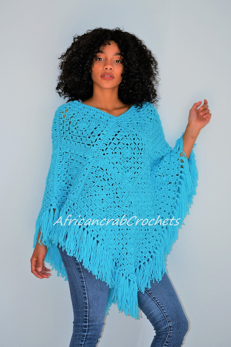 Puede incluir: Un poncho de crochet azul turquesa con flecos. El poncho tiene cuello en V y est&aacute; tejido a crochet en un patr&oacute;n geom&eacute;trico.