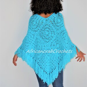 Puede incluir: Un poncho de crochet azul turquesa con flecos. El poncho tiene un cuello en V y est&aacute; hecho con un patr&oacute;n de punto de encaje.