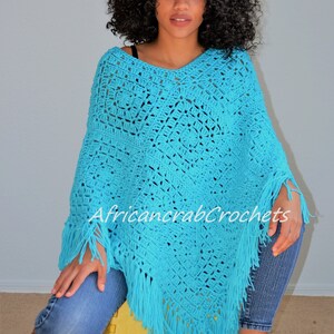 Puede incluir: Un poncho de crochet turquesa con flecos. El poncho est&aacute; hecho con un patr&oacute;n de punto cuadrado. La modelo lleva el poncho y est&aacute; sentada en un taburete amarillo.