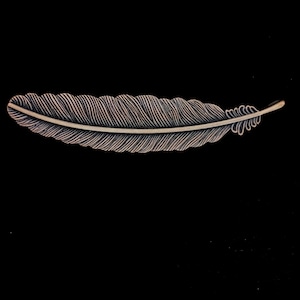 May include: A silver-colored metal feather bookmark with detailed etching. The feather is long and narrow with a pointed tip.