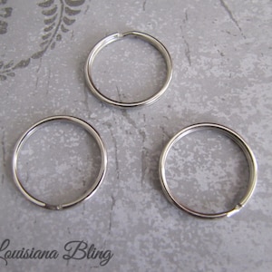 May include: Three silver key rings, each with a circular shape and a smooth, shiny finish.