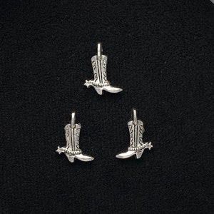 May include: Three silver cowboy boot charms with a spur detail.