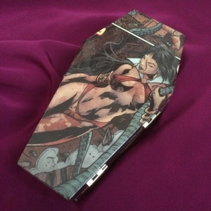 Könnte beinhalten: Sargförmige Clutch mit einer Comic-Illustration einer Frau in einem roten Bikini. Die Clutch hat einen silbernen Verschluss und ist vor einem lila Hintergrund platziert. Das Kunstwerk ist detailliert im Vintage-Comic-Stil.