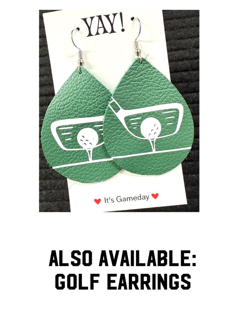 May include: A pair of green leather teardrop-shaped earrings with a white golf club and ball design. The earrings have silver hooks. The text "Yay!" and "It's Gameday" are visible on the white card behind the earrings.