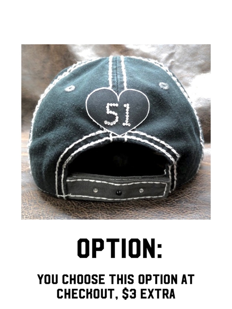 May include: Black baseball cap with a white heart-shaped patch that says "51" in rhinestones. The cap has a white stitching detail around the brim.