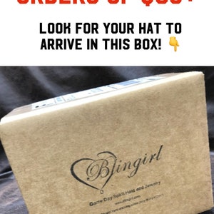 May include: A brown cardboard box with the text "Blingirl" and "Game Day Spirit Hats and Jewelry" printed on it. The box is sitting on a brown surface. Free shipping on orders of $35+.