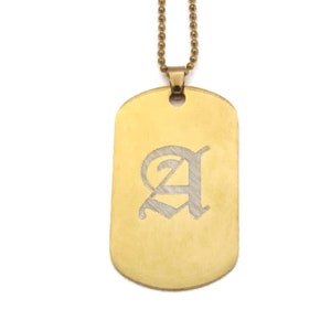 May include: Gold-colored dog tag pendant necklace with a ball chain. The tag features the letter "A" in an elegant, engraved font. The necklace hangs against a white background.