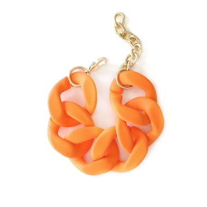 May include: A chunky orange plastic bracelet with a gold chain clasp.