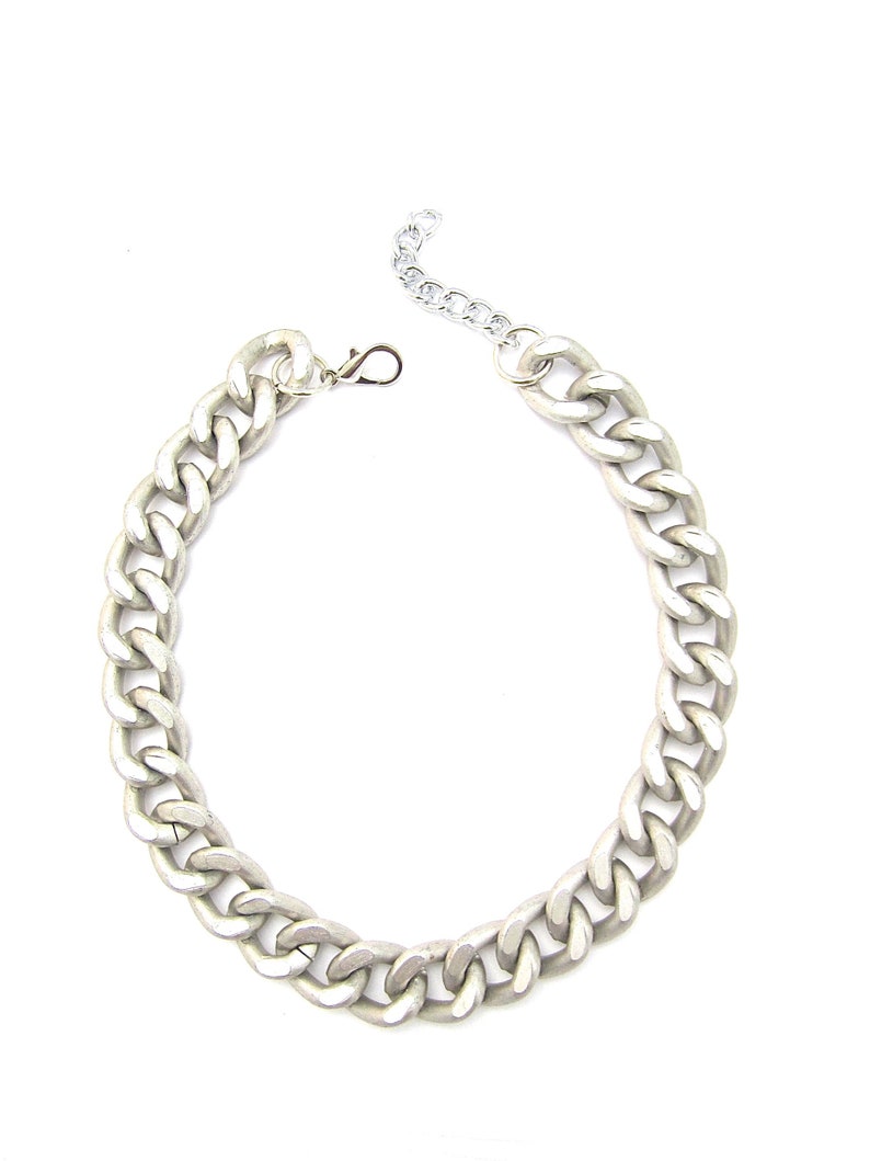 May include: A silver chain necklace with a chunky curb link design.