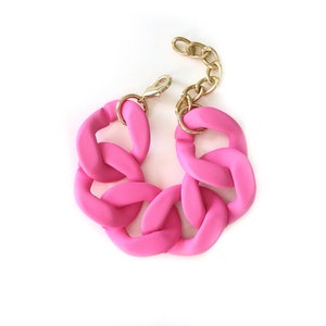 May include: A pink chunky chain bracelet with a gold clasp.