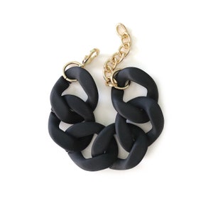 May include: A black chunky chain bracelet with a gold clasp.