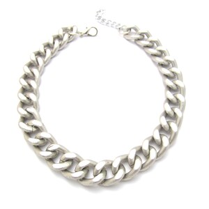 May include: A silver chain necklace with a chunky curb link design.