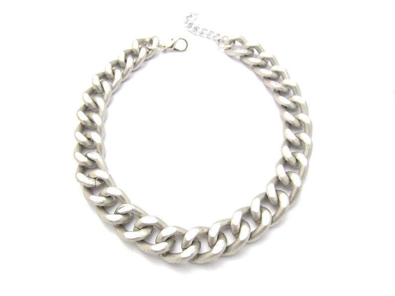 May include: A silver chain necklace with a chunky curb link design.